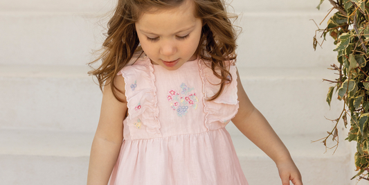 Une petite fille porte une robe rose pâle