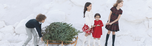 Des enfants tirent un sapin de Noël dans la neige