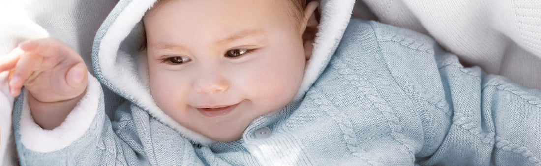 Bébé dans son manteau en maille bleu